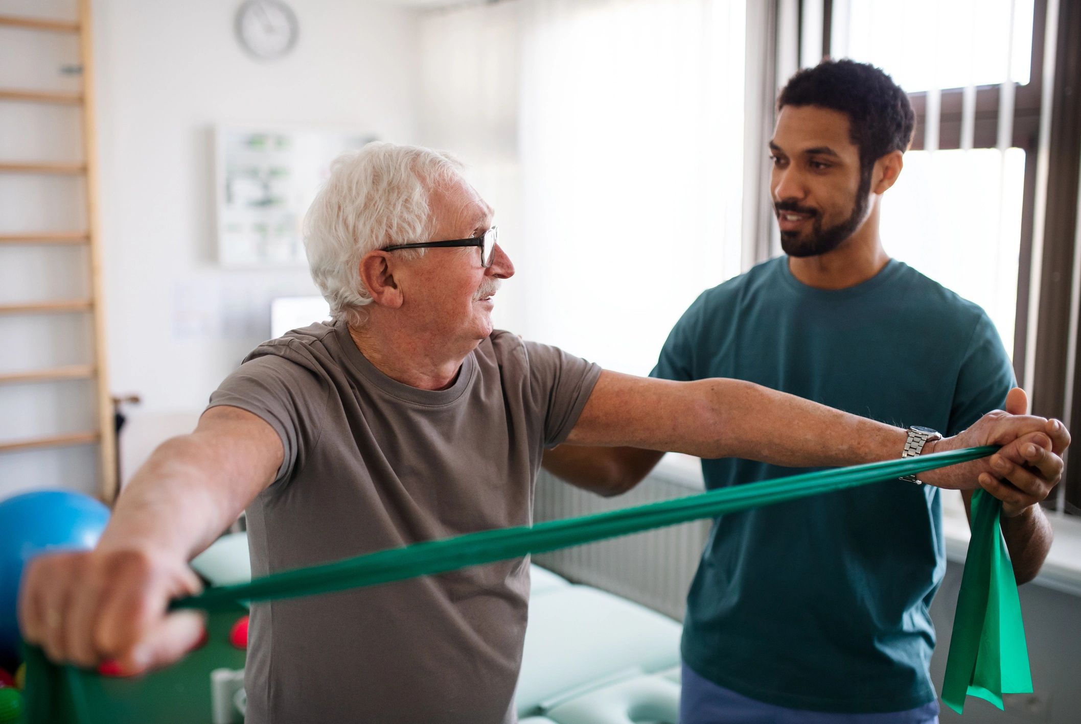 A young physiotherapist exercising with senior patient in